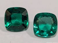 Close-up of both created emeralds showing cushion cuts and colour
