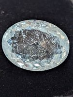 Front close-up of oval faceted aquamarine on dark background