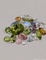 Top view of assorted faceted gemstones laid out on white surface