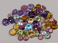 Loose multicolour faceted gemstones spread out on white background