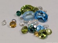 Group of assorted coloured faceted gemstones on white background