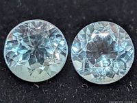 Two round blue topaz gemstones close-up showing color and cut