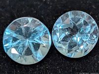 Close view of two round blue topaz gemstones showing faceting and color