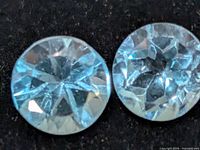 Two loose round blue gemstones on dark background