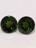 Close-up of both chrome diopside gemstones showing facet pattern and color