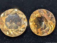 Close-up of two round yellow gemstones showing facets and colour