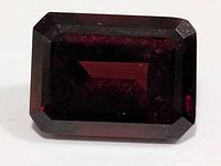 Front view of faceted garnet showing deep red color and step cut