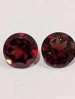 Front view of both garnet gemstones showing round shape and faceting