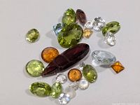 Group of assorted faceted gemstones various colours and cuts on white background