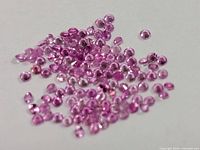 Group of loose pink sapphire stones scattered on white surface