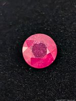 Close-up of round faceted ruby on black background
