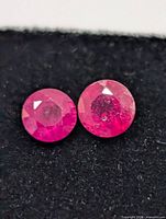 Close-up of two round faceted rubies on black background