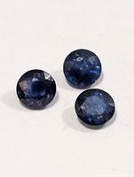 Three round blue sapphires on neutral background