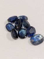 Group of nine oval-cut blue sapphires on neutral background