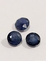 Three round faceted blue sapphires on white background