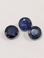 Three round faceted blue sapphires on white background