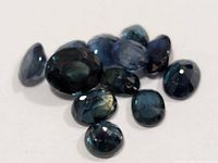 Group of deep blue faceted sapphire gemstones on white background