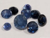 Group of nine faceted blue sapphires on white background