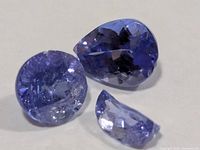 Three pieces of faceted tanzanite showing cuts and damage