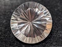 Round faceted transparent gemstone on dark background