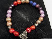 Full view of beaded bracelet showing multicolor pearls and charm