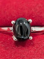 Front view of silver ring with oval black star onyx in four-prong setting