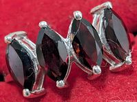 Close-up of three marquise garnets in prong settings on silver band