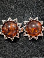 frontal view of both amber stud earrings showing sunburst silver mount