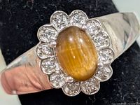 Front view of ring showing tiger eye cabochon and halo of clear stones