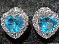 Front view showing heart-cut blue centre stones and clear CZ halo
