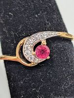 Front view of silver ring showing ruby center stone and CZ accent stones