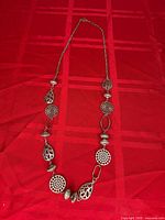 Full view of entire necklace laid flat on red background