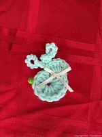 front view of crocheted mint green bird brooch with ribbon bow