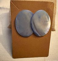 Front view of two oval blue lace agate stones mounted as earrings on display card