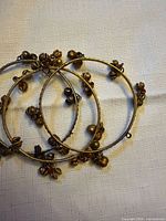Three brass-tone charm bangles laid flat