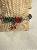 Front view showing red and green beads with bell charm