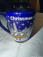 Front view showing Christmas Village graphic and blue ceramic body