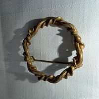 Front view of circular twisted branch gold-tone brooch