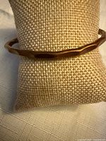 Bracelet displayed on burlap pillow, front view shows hammered facets