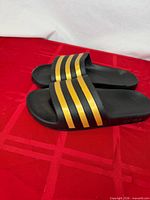 Top view of Adidas slides showing gold stripes and overall wear