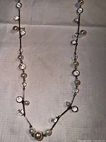 Full view of long silver tone necklace with crystals and faux pearls