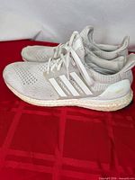 Left side view of both sneakers showing knit upper, side cage, Boost midsole