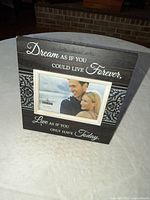Front of black wooden picture frame showing quote and photo opening