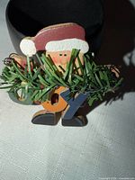 Front view of wooden snowman brooch pin with JOY letters and greenery