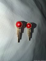 Front view of both earrings showing red stones and gold chain tassels