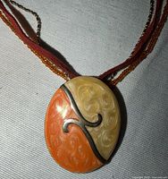 Close-up of pendant showing enamel colors, swirl pattern and metal inlay
