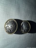 Front view of both patterned silvertone clip-on earrings