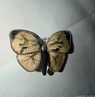 Front view of butterfly brooch showing thread pattern, wire edging, faux pearl
