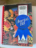 Front cover showing title, ribbon graphic, produce background, red comb binding