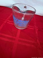 Front view of Anchor Hocking glass measuring cup showing blue logo and split spout